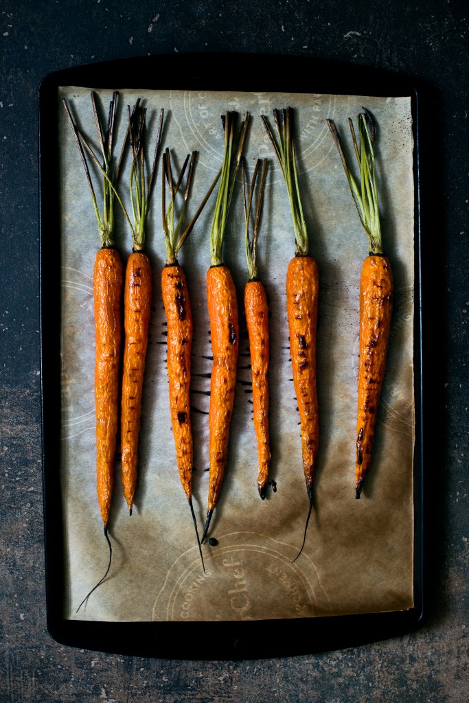 Bright orange roasted carrots on a black pan