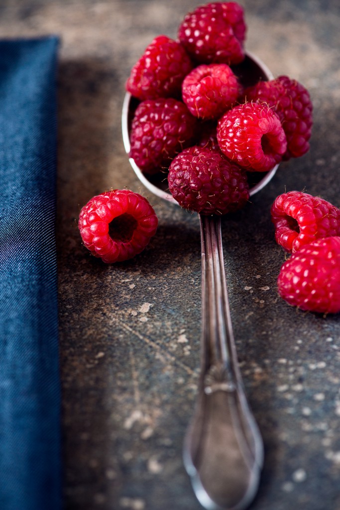 Raspberries on a spoon with a blue napkin